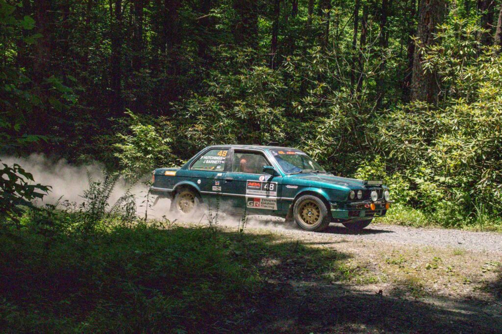 rally car racing through the woods at flying finish